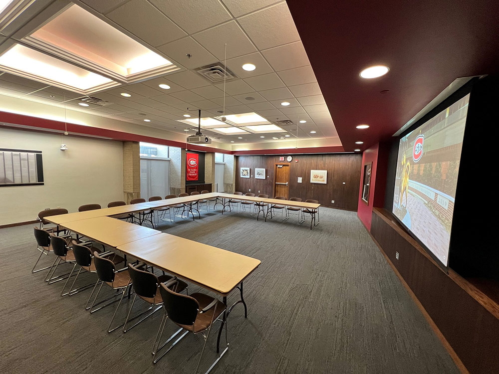 Alumni Room at Atwood Memorial Center from a different angle showing tables, chairs, and a hybrid meeting setup with microphones and camera