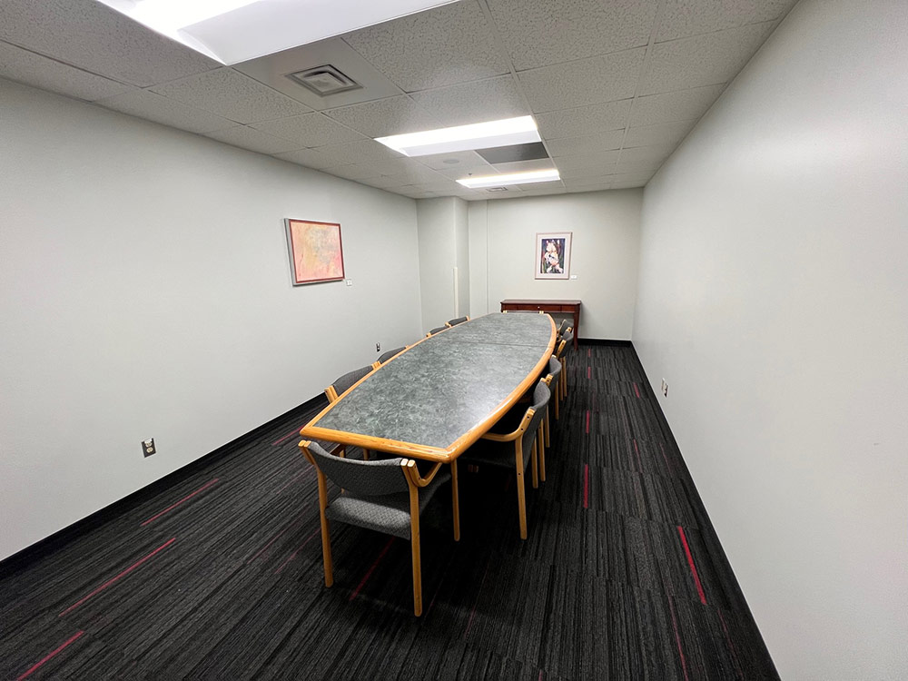 Interior of the Iris Room at Atwood Memorial Center showing a narrow table with chairs and artwork displayed on the wall