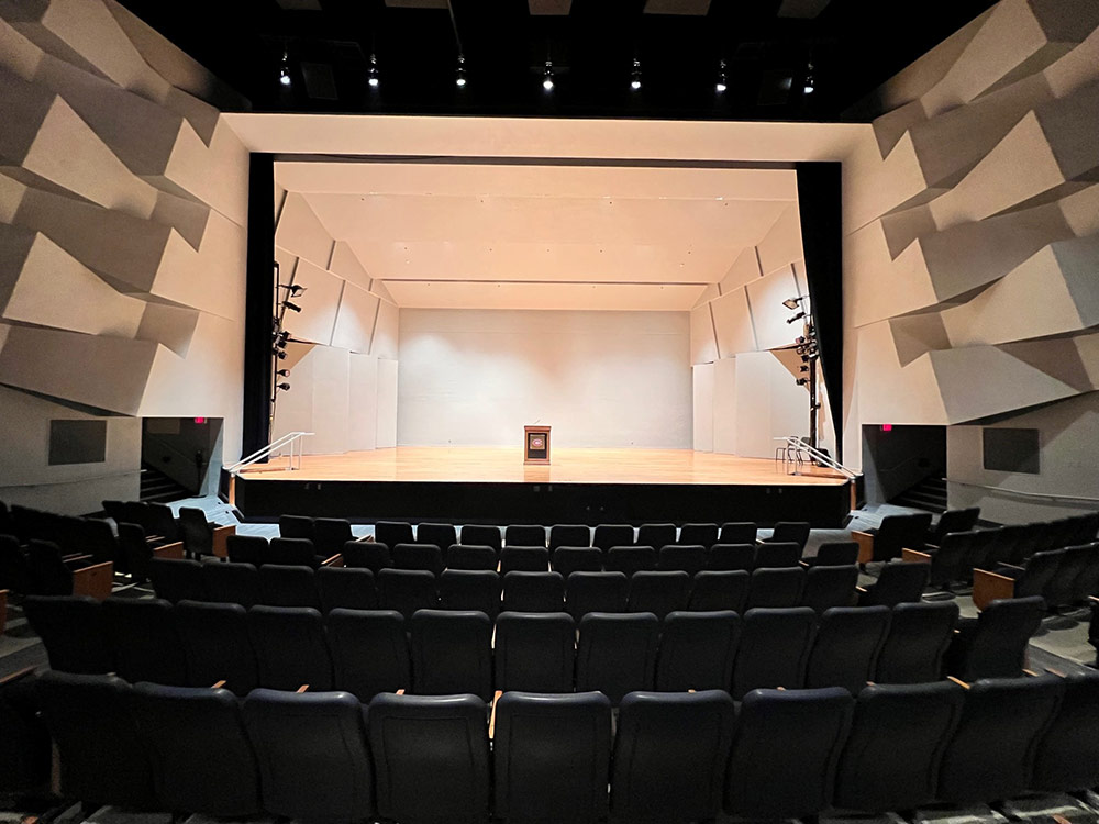 View inside Ritsche Auditorium in Stewart Hall featuring the stage area with lighting equipment and visible seats