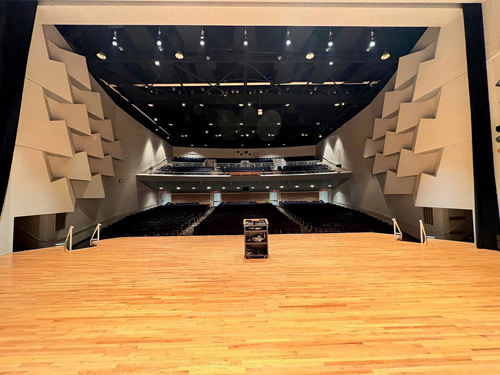 Wide interior shot of Ritsche Auditorium in Stewart Hall showing the audience seating, stage setup, and overhead lights