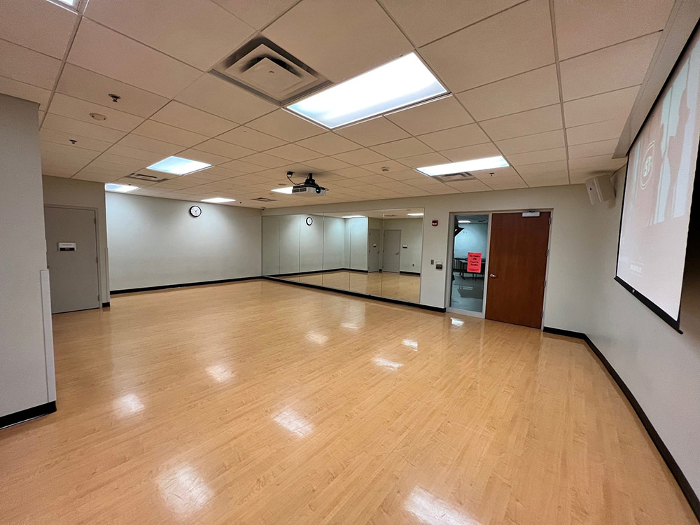 Wide open Studio Room at Atwood Memorial Center with floating wood floor and mirrors along one wall