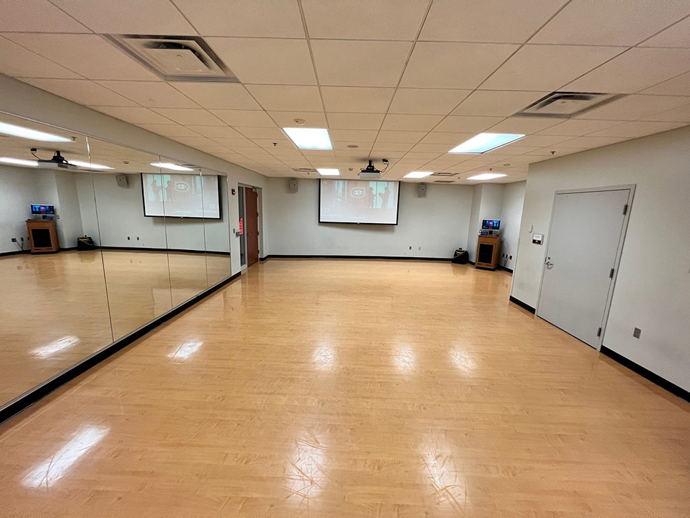 Straight-on view of the Studio Room’s open floor and mirrors, capturing natural light from overhead windows