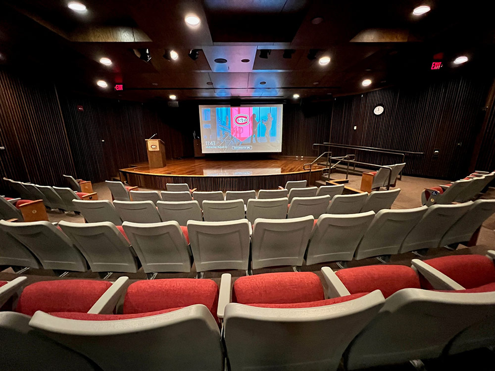 Interior of the Atwood Theatre showing rows of fixed seating facing a stage with a projection screen