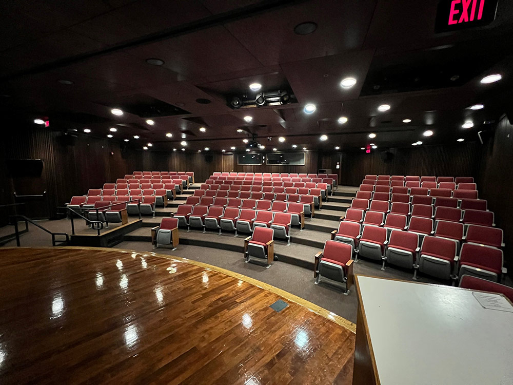 Interior view of the Atwood Theatre showing the stage with screen and rows of empty chairs extending toward the back