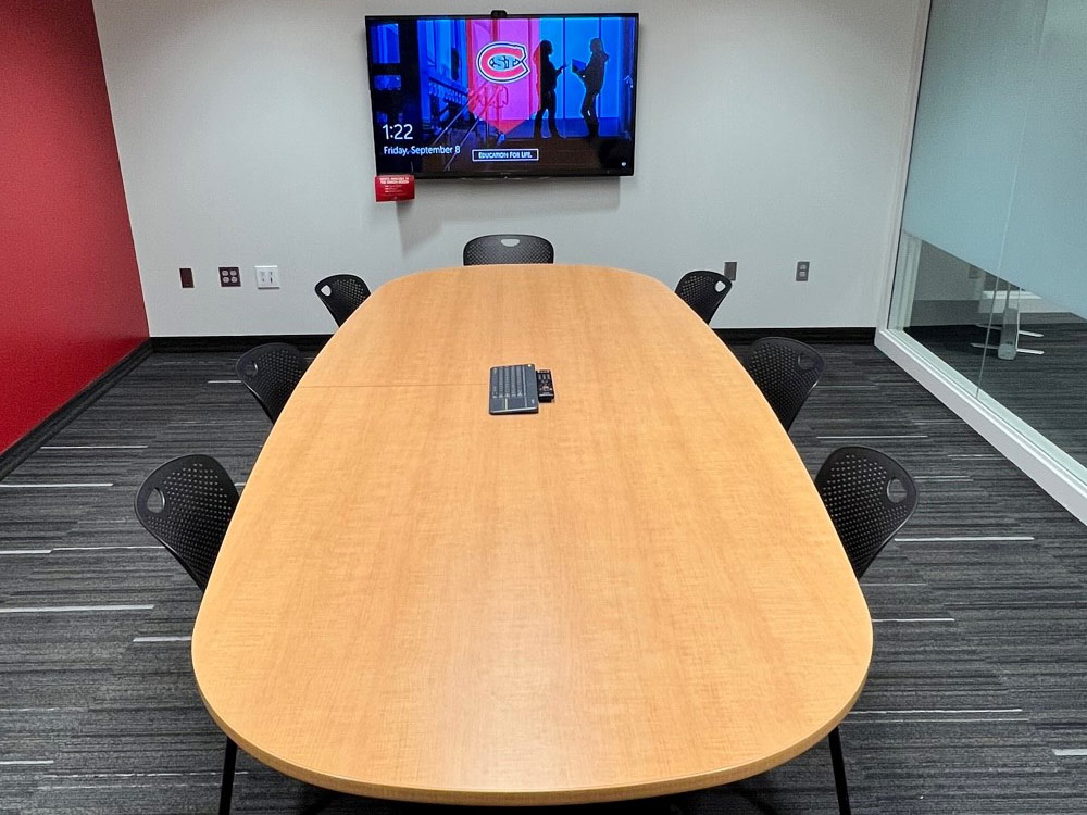 Interior of the Union Room in Atwood Memorial Center showing a small meeting space with a table and chairs, glass walls with frosted panels, and natural light from windows