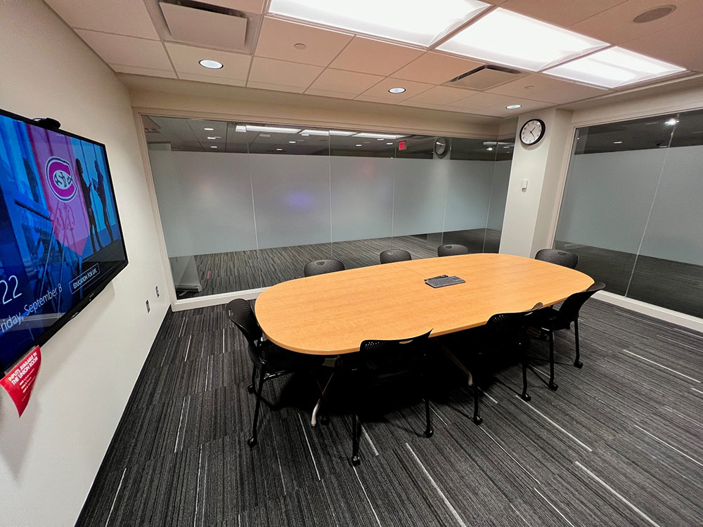 Interior of the Union Room in Atwood Memorial Center from a different angle showing the conference table and chairs, clear glass wall sections, and a bright meeting area