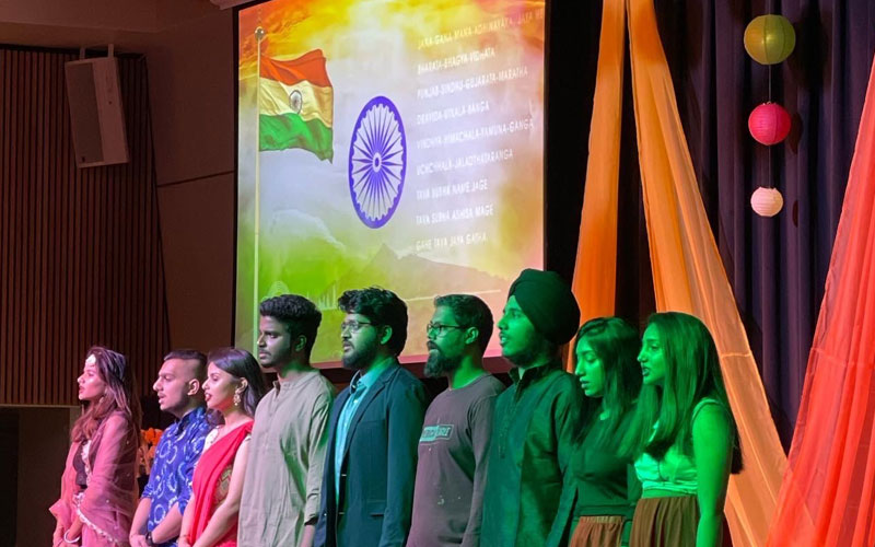 Nine students on a stage with a projector in the background at a Cultural Nights event in Atwood Memorial Center