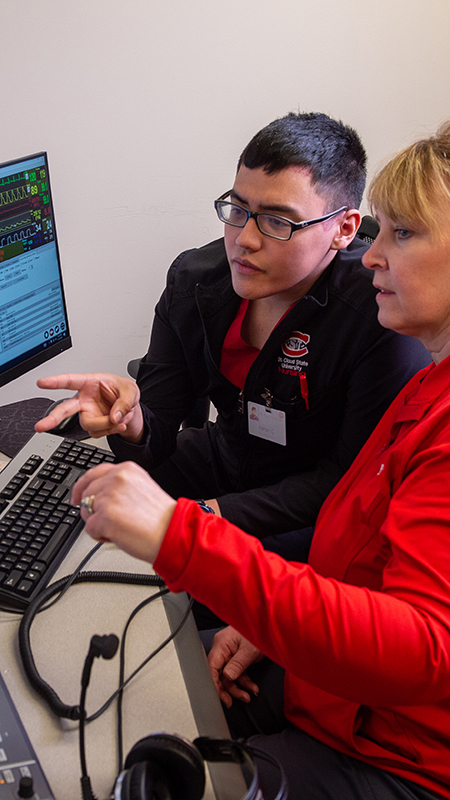 Nursing student and professor working at an observation station with two computer monitors