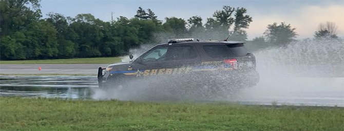 A SUV for a police agency drives along a wet course road at the Precision Driving Center